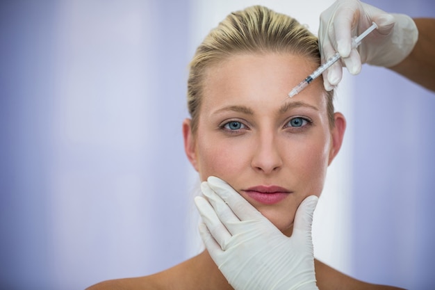 Foto gratuita paziente femminile che riceve un'iniezione di botox sulla fronte