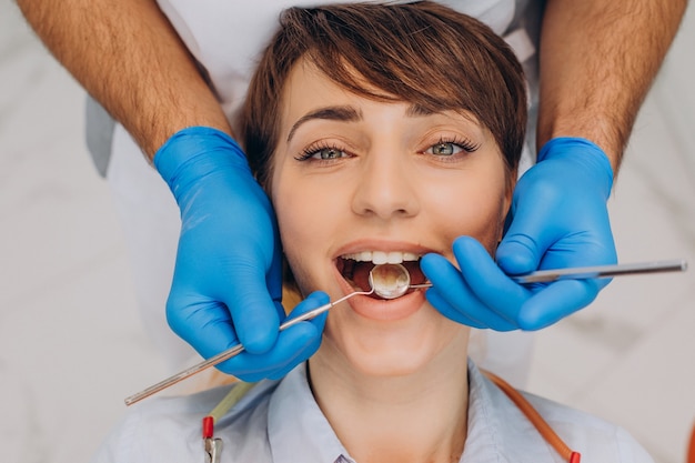 Пациентка сидит в кресле стоматолога и делает профессиональную гигиену