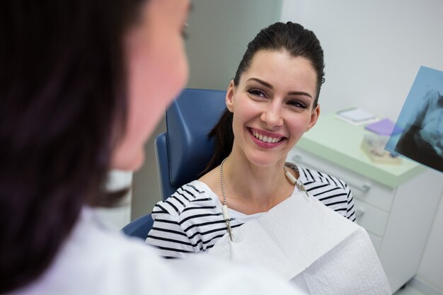 Женский пациент улыбается во время разговора с врачом