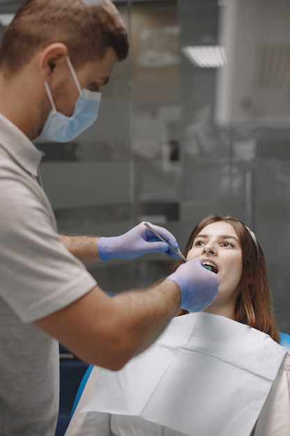 Female patient with braces has dental examination at dentist office. Stomatologist wearing blue gloves