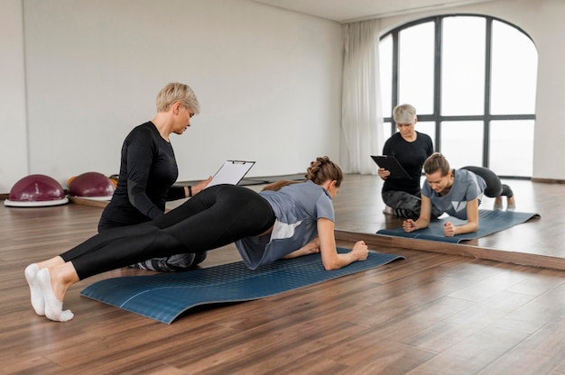 Female personal trainer helping her client and looking in the mirror