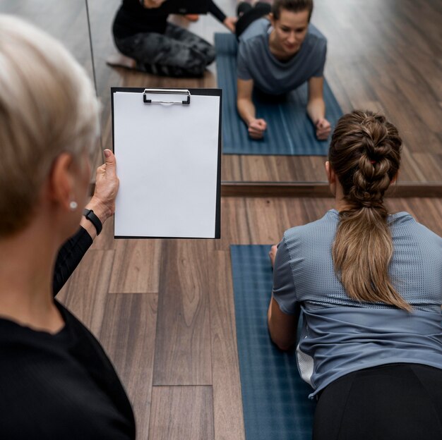 Female personal trainer helping her client  over the shoulder shot