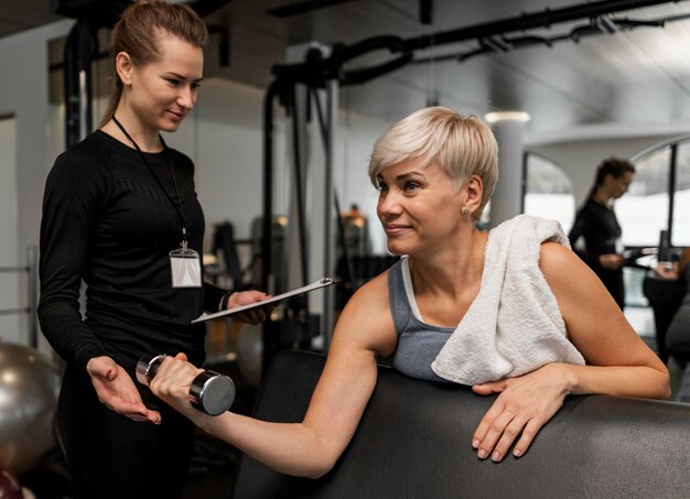 Female personal trainer and her client using dumbbell