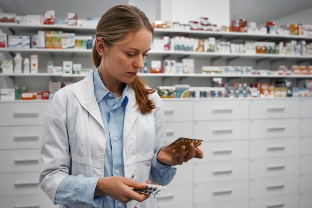 Foto gratuita farmacista femminile che controlla le pillole in farmacia