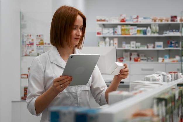 Бесплатное фото Женщина-фармацевт, работающая с планшетом в аптеке