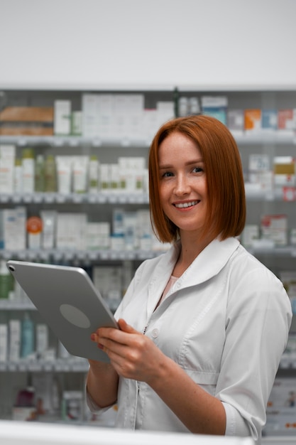 Foto gratuita farmacista femminile che lavora con il tablet in farmacia