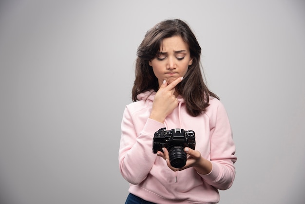 Female photographer looking at pictures on gray wall.