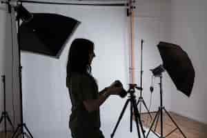 Foto gratuita fotografo femminile in studio fotografico moderno con attrezzature professionali