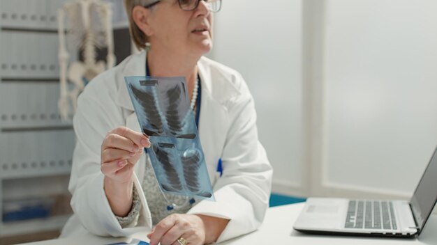 X線スキャンの結果を患者に診断し、骨の病気を説明する女性医師。 X線写真を分析して、処方薬と治療で病気を治すのに役立ちます。