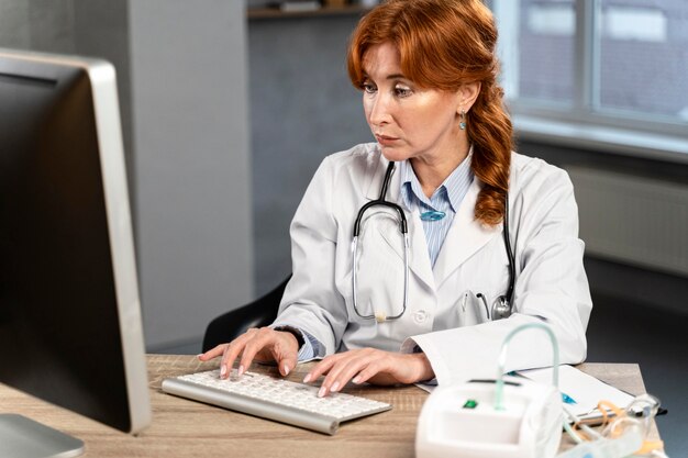 Female physician typing on computer at desk
