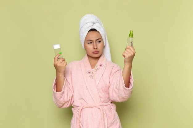 female in pink bathrobe holding spray flasks