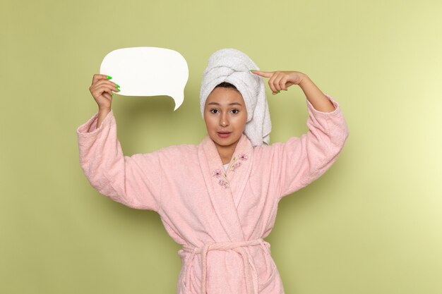 female in pink bathrobe holding white sign