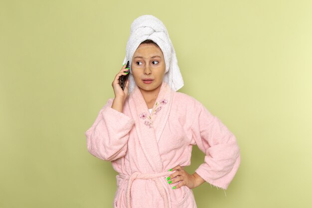 female in pink bathrobe talking on the phone