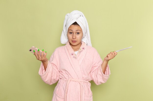 female in pink bathrobe using her phone