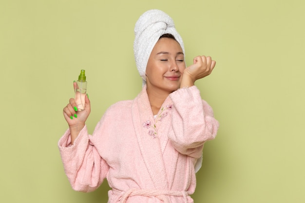 female in pink bathrobe using little spray