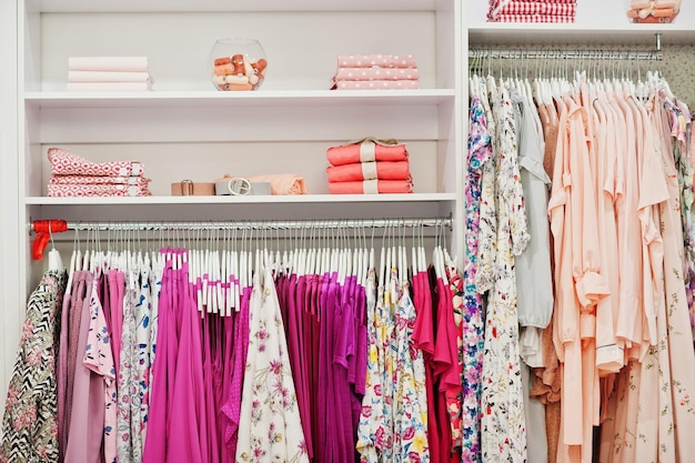 衣料品店のブランドの新しいモダンなブティック春夏のドレスコレクションのラックと棚に女性のピンクのカラフルな服のセット