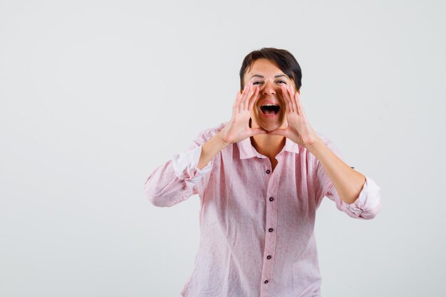 Female in pink shirt shouting or announcing something and looking confident , front view.