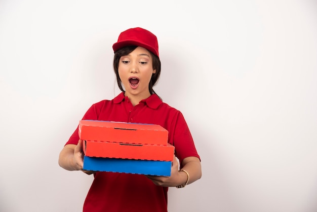 Female pizza delivery worker standing with three cardboards of pizza.