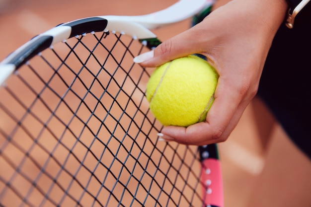 テニスボールを持つ女性プレーヤーの手、試合中に準備する