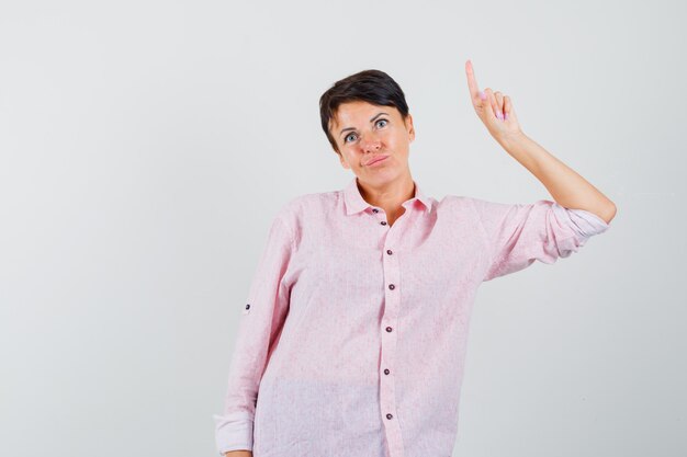 Female pointing up in pink shirt and looking indecisive. front view.