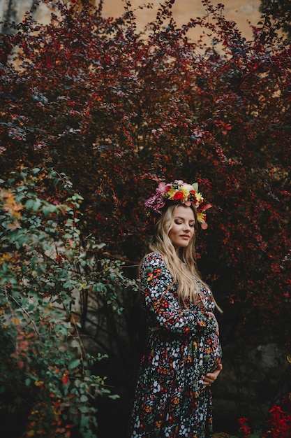 Ritratto femminile affascinante donna incinta in abito di fiori pone