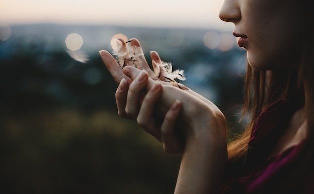 Female portrait. Nature. Pretty woman plays with dandelion stand