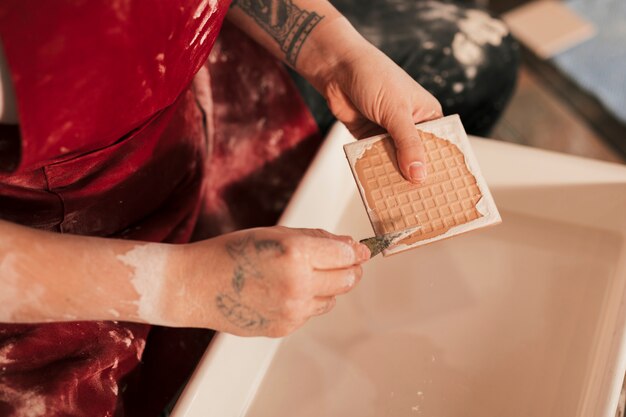 욕조 위에 날카로운 도구로 페인트를 제거하는 여성 포터