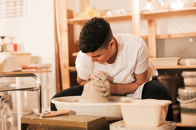Female potter's giving shape to the lump of wet clay on pottery wheel
