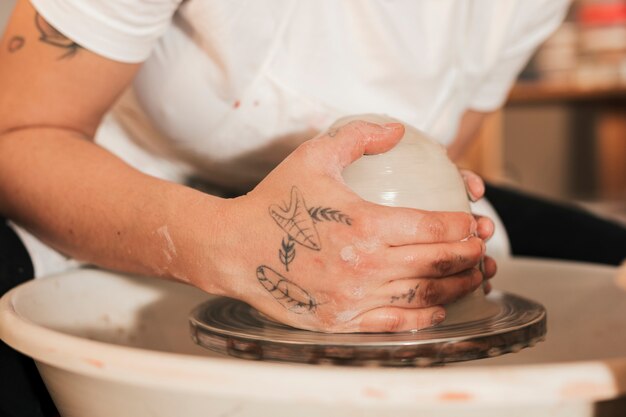 陶器のホイールに粘土で女性の陶工の手のクローズアップ