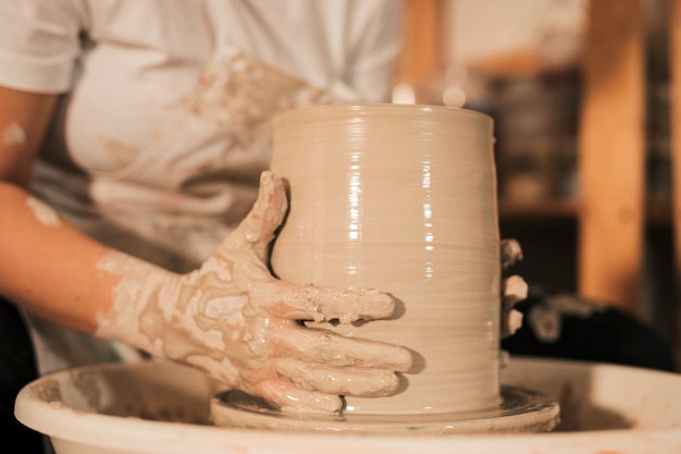 Foto gratuita vasaio femminile che modella vaso nell'officina delle terraglie