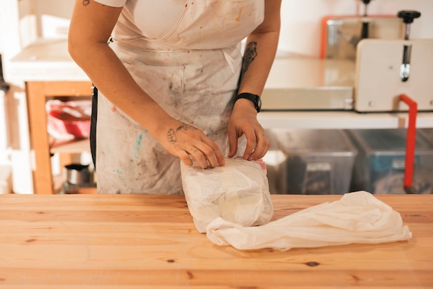 Female potter unwrapping the clay in the workshop