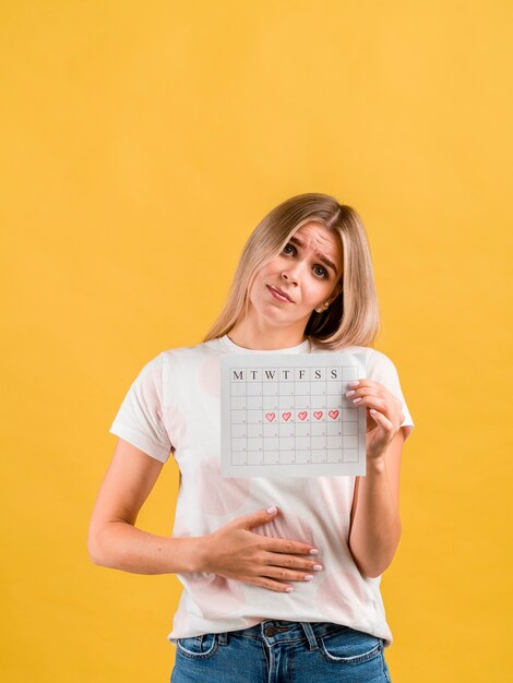 Female puts hand on abdomen and showing period calendar