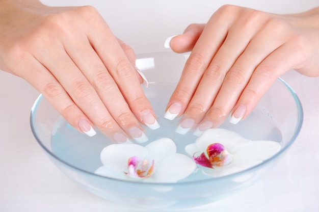 Female putting her beautiful fingers into the bowl with water