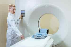 Бесплатное фото Женщина-рентгенолог готовит компьютерный томограф к медицинскому осмотру пациента