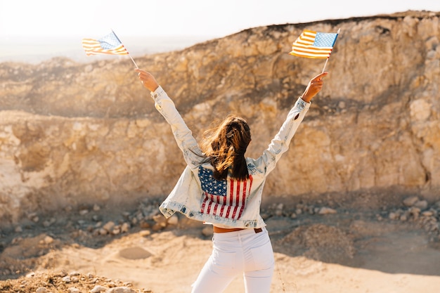 Female raising hands with flags on mountain