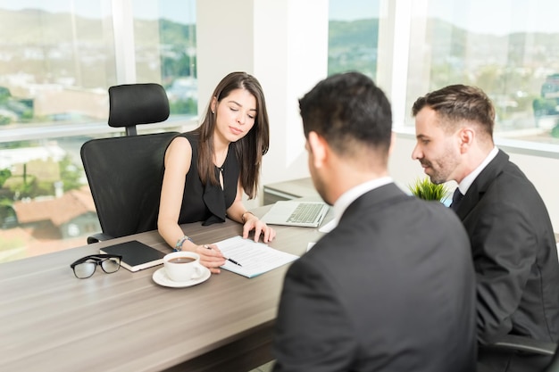 Female real estate agent explaining rental agreement to businessmen in office