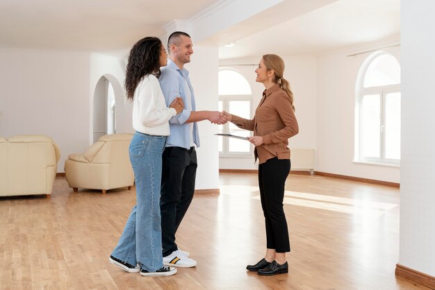 新しい家の取引のためにカップルと握手する女性不動産業者
