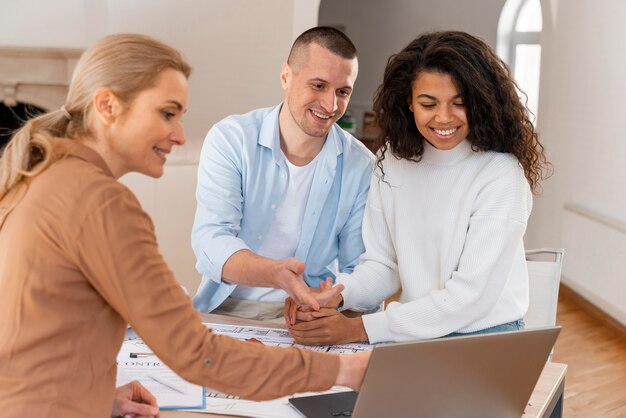 Female realtor showing new house to smiley couple on laptop