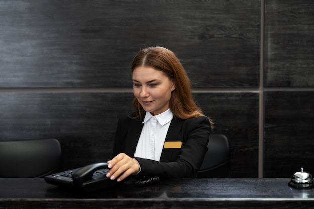 Foto gratuita addetta alla reception femminile in abito elegante durante l'orario di lavoro