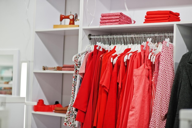 옷가게의 새로운 현대 부티크 봄 여름 드레스 컬렉션의 선반과 선반에 있는 여성용 빨간색 화려한 의류 세트
