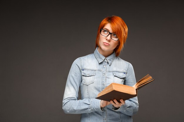 Female redhead student reading book, studying