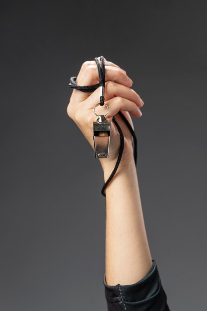 Female referee hand with whistle close up