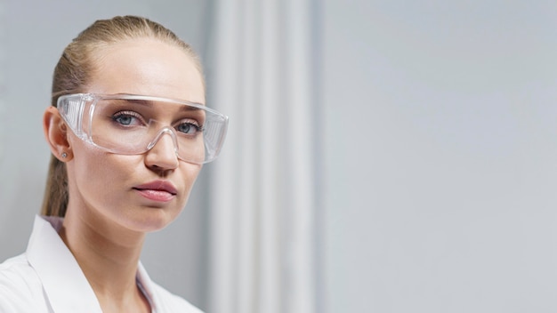 Foto gratuita ricercatore femminile in laboratorio con occhiali di sicurezza e copia spazio