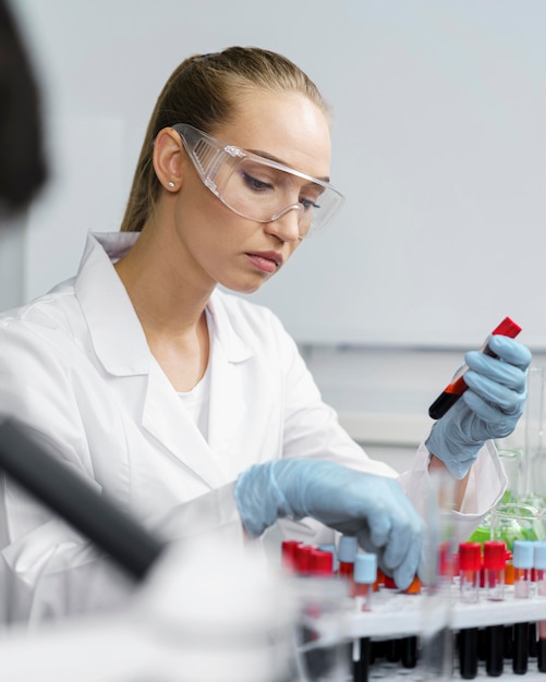 Female researcher in the laboratory with test tubes and safety glasses