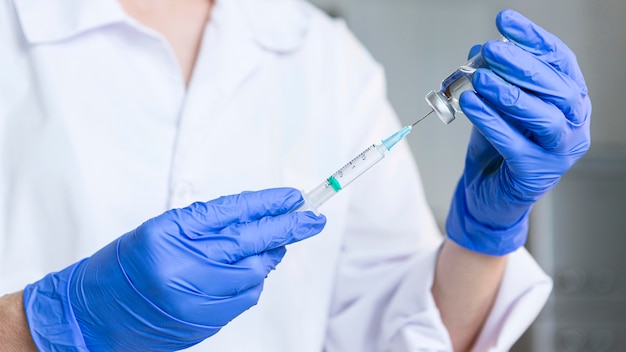 Female researcher with safety glasses and gloves holding syringe