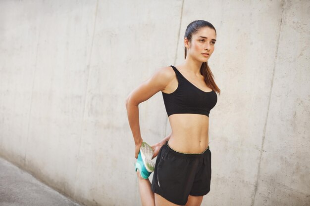 Женщина-бегунья растягивается на пути к идеальной форме тела Концепция городского спорта