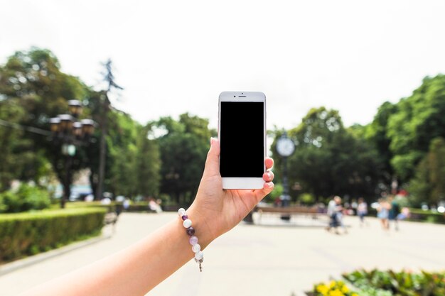 Female's hand holding cellphone at outdoors