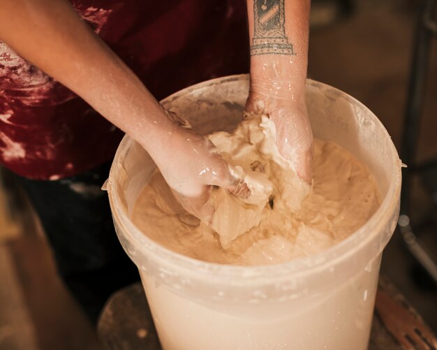 Foto gratuita la mano della femmina che mescola la vernice con le mani nel secchio di plastica bianco