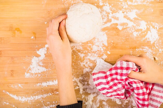 Рука женщины готовит тесто на деревянном столе