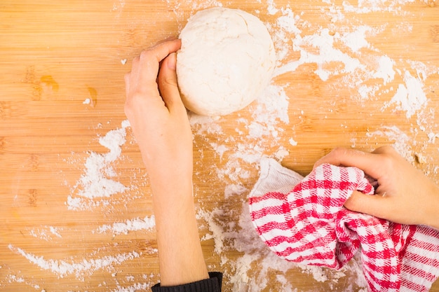 Female's hand preparing dough on wooden desk